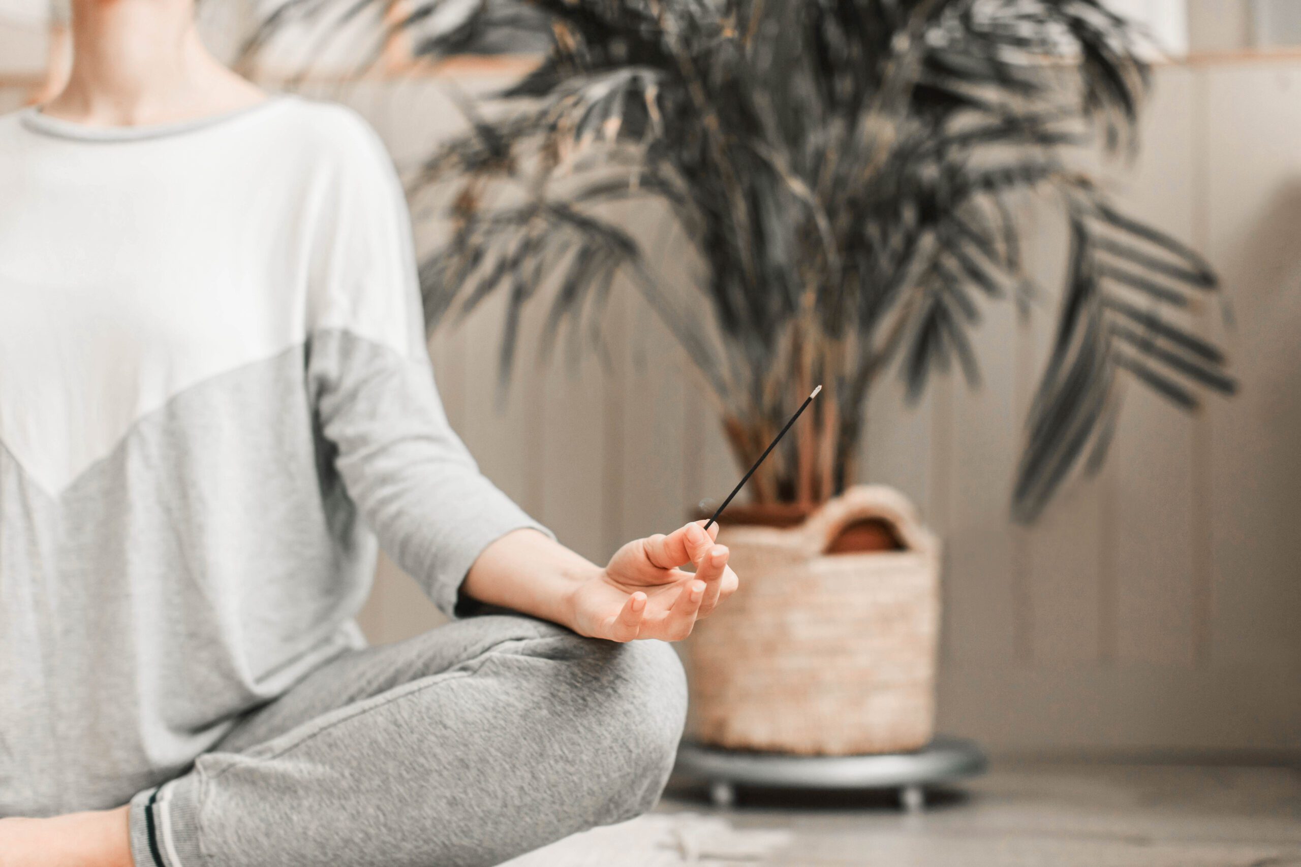 Frau im Meditationssitz mit Räucherstäbchen