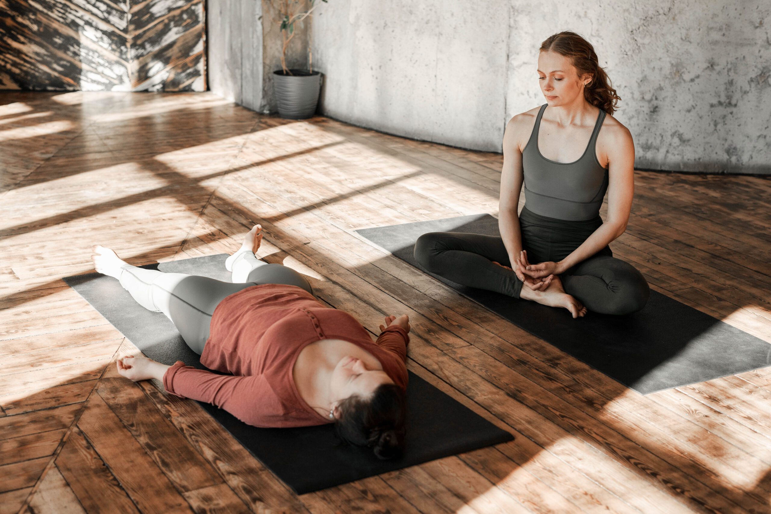 Frau liegt auf Yogamatte und macht Breathwork